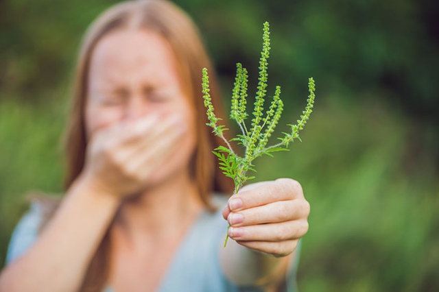 Image of woman holding plant stem away from her nose