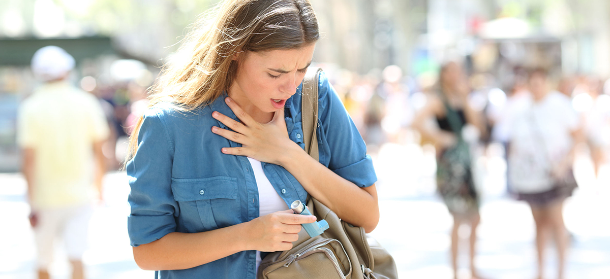 Woman taking asthma inhaler from handbag.